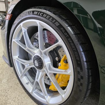 Close-up of a car wheel with Michelin tire and yellow brake caliper.