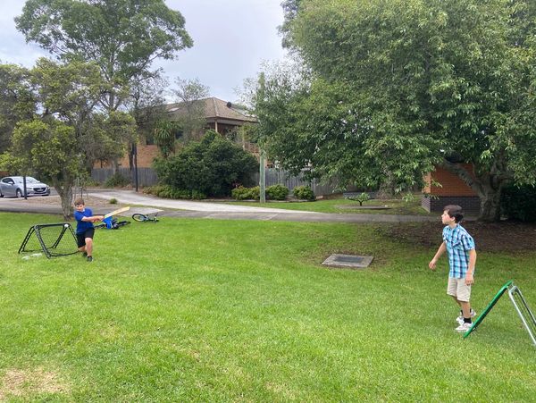 Two boys playing baseball in a grassy backyard.