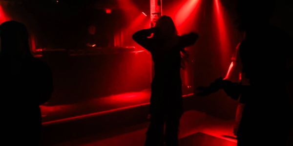 People dancing in a dimly lit club with red lights.
