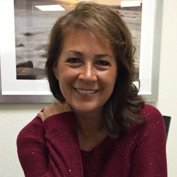 Smiling woman in a red sweater sitting indoors.