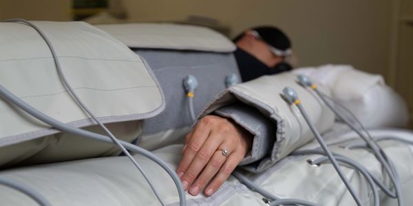 Person undergoing a therapy session with devices on arms and legs.