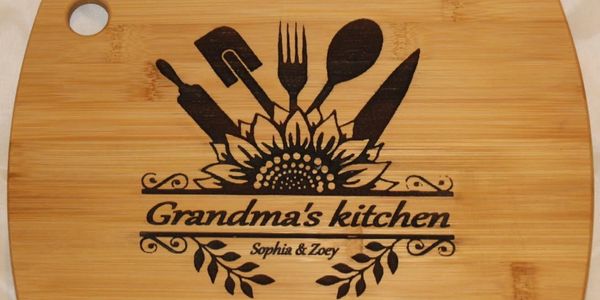 Wooden cutting board engraved with "Grandma's kitchen" and cooking utensils.