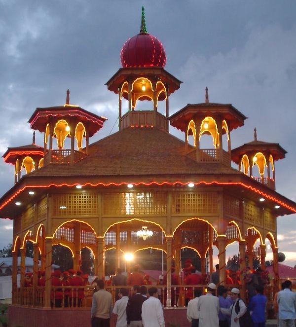 A beautifully lit pavilion with people gathered around it during dusk.