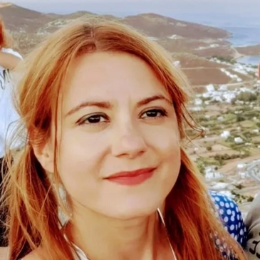 Coloured profile photo of our proofreader, Maria Lymberopoulou, on a mountain slope.