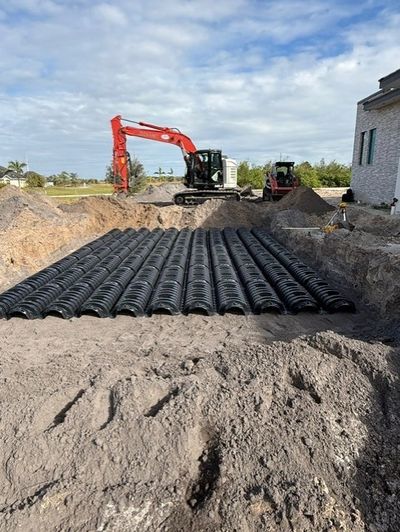 Construction site with drainage pipes being installed in a trench beside a building.