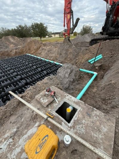 Construction site with drainage system installation and excavation equipment.