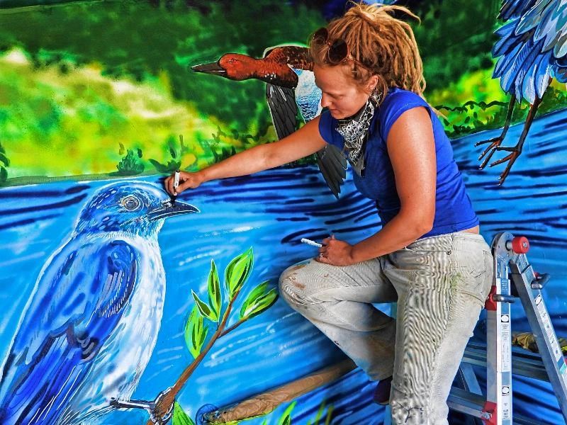 Helen Seay, a Tetonia artist, works on a mural at a Bureau of Land Management vault toilet on the south side of Henry's Lake. | Courtesy of Bruce Hallman, Bureau of Land Management