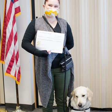 Award recipient with her service dog and scholarship award.