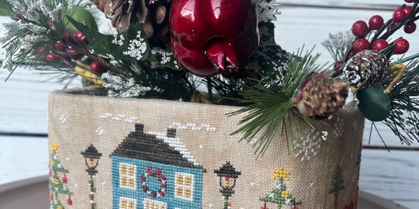 Holiday-themed decorative arrangement with stitched house design.