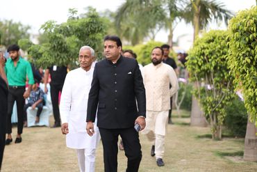 Two men in traditional and formal attire walking in a garden.