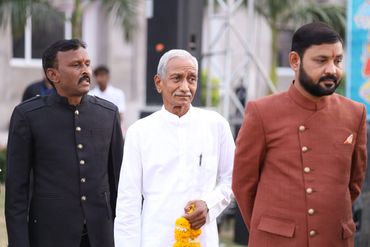 Three men dressed in traditional formal attire standing outdoors.