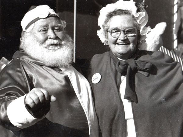 An elderly couple dressed in festive costumes, smiling warmly at the camera.