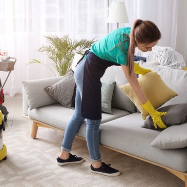 Woman cleaning and arranging cushions on a couch.