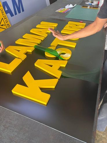 Yellow 3D letters being arranged on a black surface for a sign.