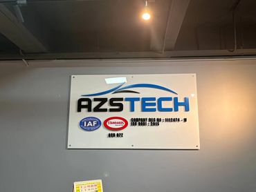 AZSTECH company signboard with quality certification logos on a wall.