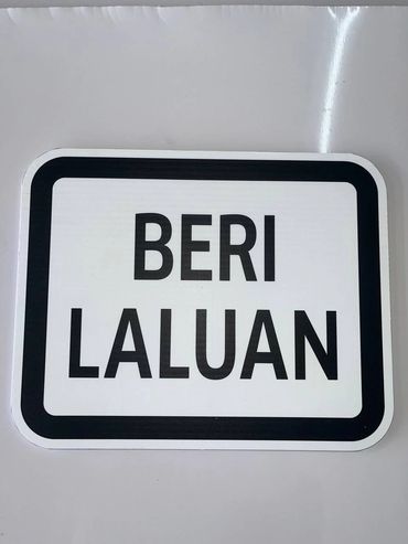 A rectangular sign with the words 'BERI LALUAN' in black on a white background.