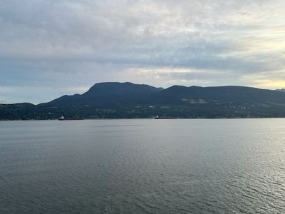 Calm water with distant mountains under a cloudy sky.