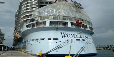 Large cruise ship Wonder of the Seas docked at port under cloudy sky.