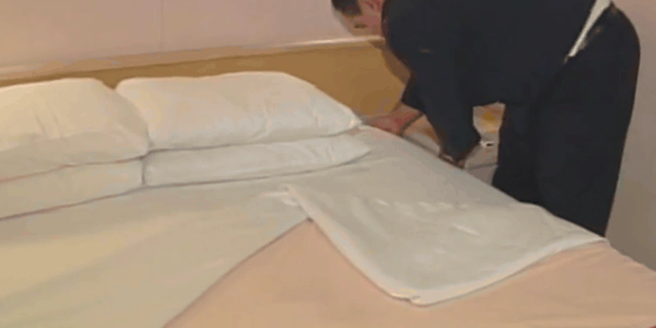 A stateroom attendant making the bed on Vision of the Seas
