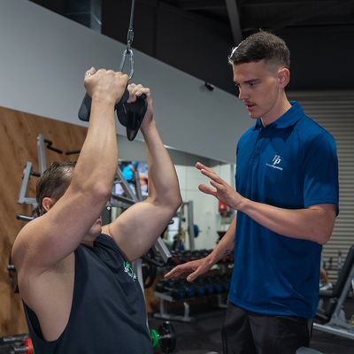 Advising a client on correct exercise technique on a pulldown. 