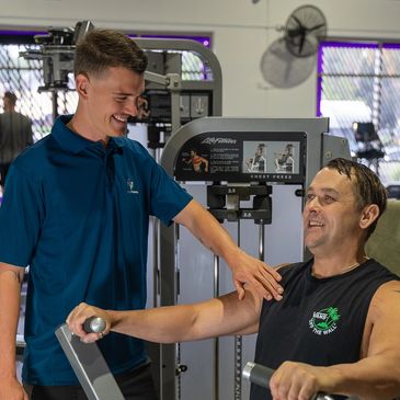 Advising a client on correct exercise technique on a chest press. 