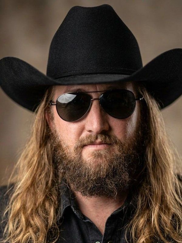 Man with long hair, beard, sunglasses, and cowboy hat.