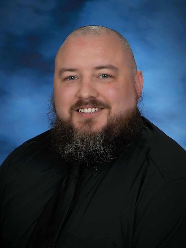 Portrait of a smiling man with a beard and shaved head.