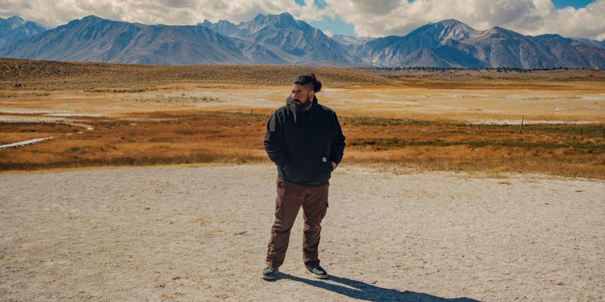 Man standing in a vast mountainous landscape.