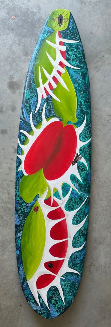 Colorful surfboard with abstract red, green, and white organic shapes.