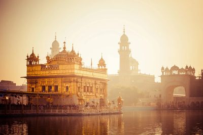 Golden Temple reflecting in water during sunrise.