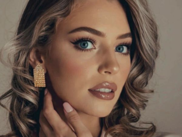 Close-up portrait of a woman with blue eyes and curly hair.