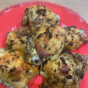 Red plate filled with Greek Seasoned Chicken Thighs that were baked to a golden brown.