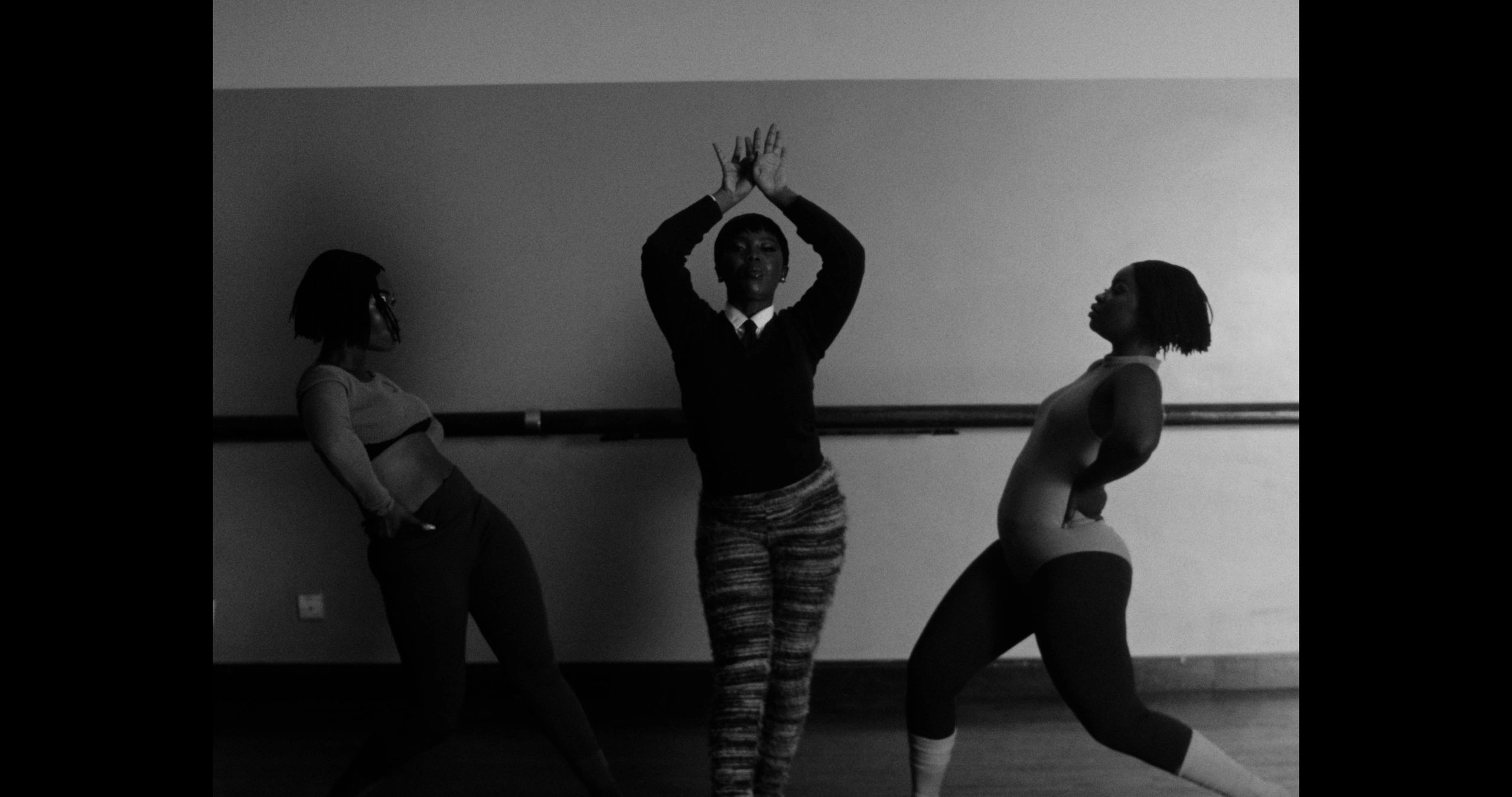 Three women dancing in a studio captured in black and white.