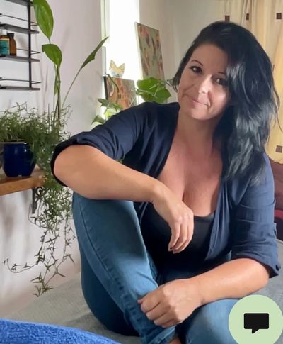 Woman sitting casually with a slight smile indoors.