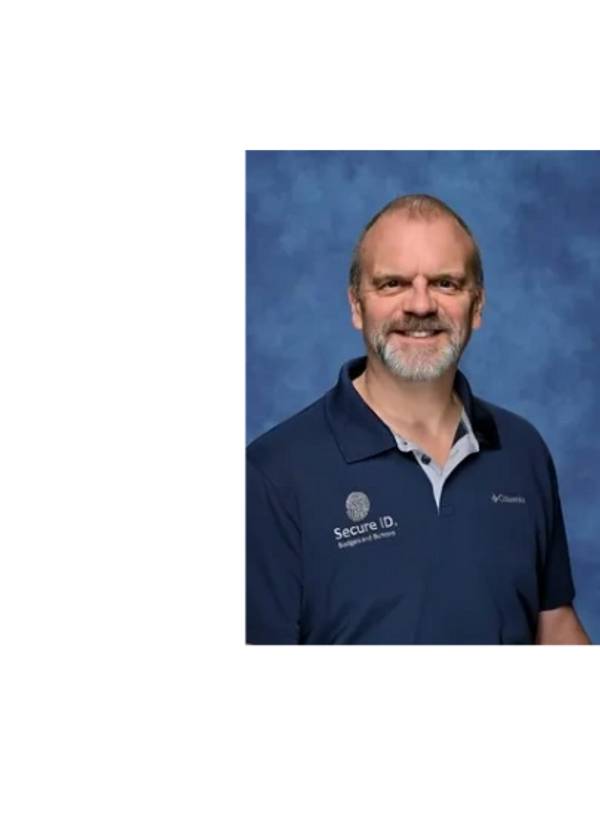 Smiling man in a navy blue Secure ID polo shirt against a blue backdrop.