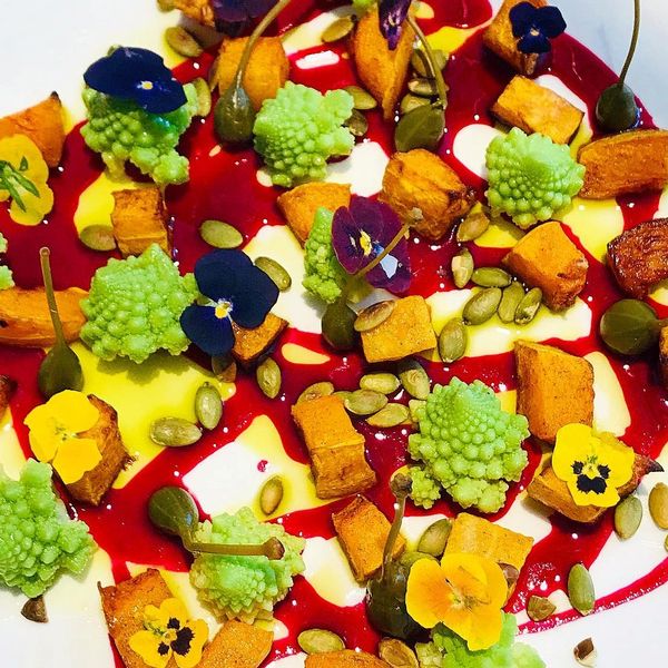 Colorful gourmet dish with vibrant vegetables and edible flowers.