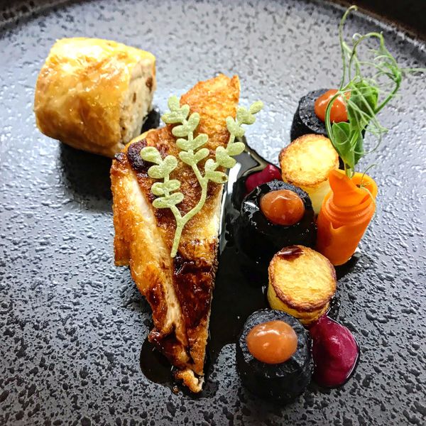 Gourmet dish with grilled chicken and elegant garnishes.