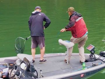 Bobby Gentry and his guest, with net in hand, pulling up a small mouth bass out of Dale Hollow Lake 