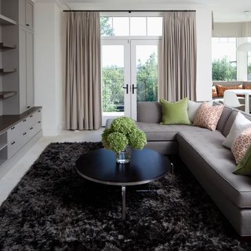 Comfortable lounge area adorned with cream pencil pleat curtains and a variety of scatter cushions.