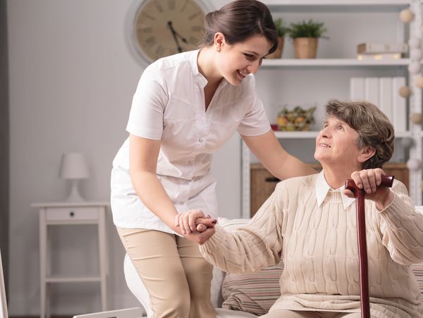 A carer helping an elderly woman getting up