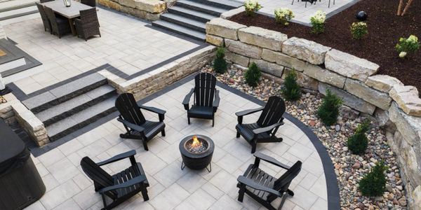 Outdoor patio with black chairs arranged around a small fire pit.