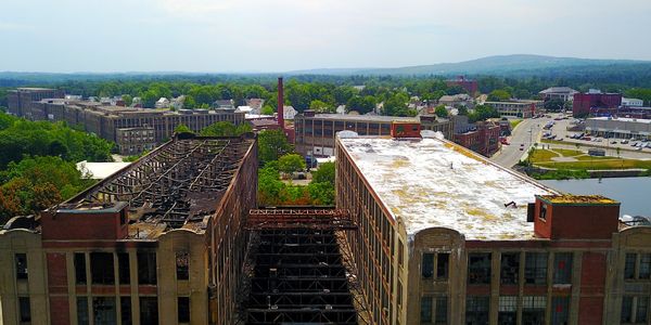 Aerial view of old industrial buildings with one roof damaged and the other intact.