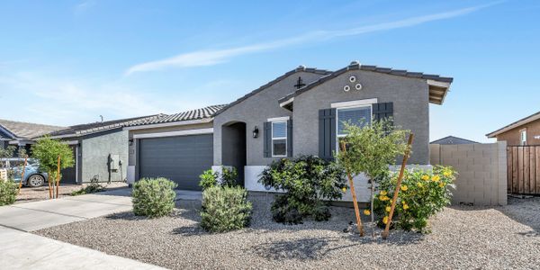 Single-story gray stucco house with desert landscaping and a two-car garage.