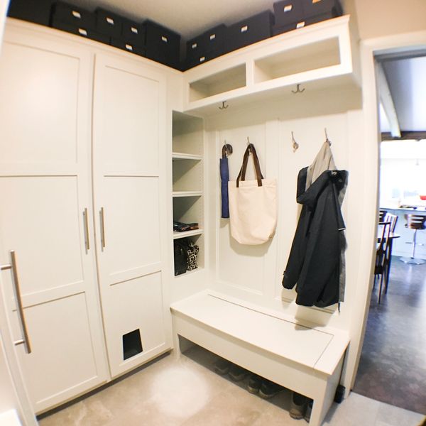 Organized mudroom with hooks, storage bench, and cabinets for coats and accessories.