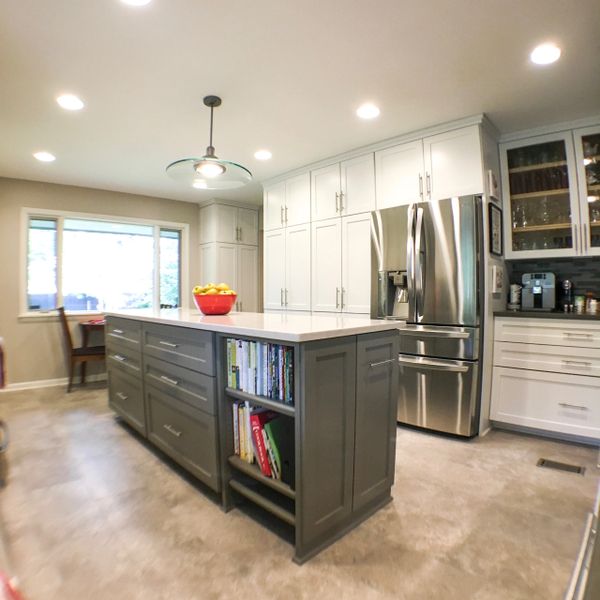 Modern kitchen with a large island and stainless steel refrigerator.