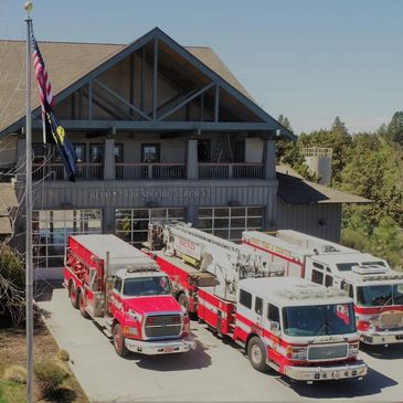 Fire department with several fire trucks parked outside on a sunny day.