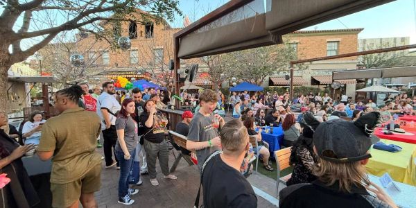 Crowded outdoor gathering with people socializing and colorful decorations.