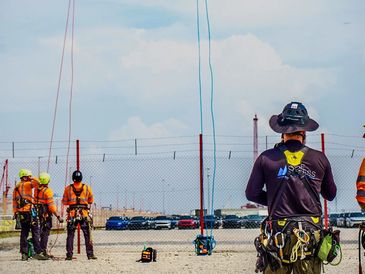 Workers practicing rope access and safety harness training outdoors.