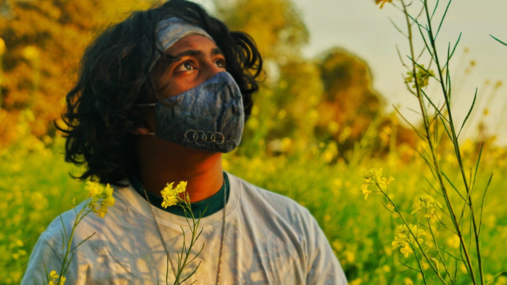 Long Haired Boy with Mask in a field of yellow flowers

