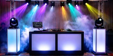DJ booth with colorful stage lights and smoke effects.